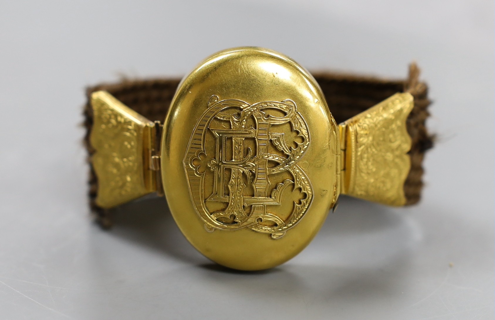 A Victorian yellow metal and hairwork bracelet with central photographic locket, central motif 44mm, gross weight 35.3 grams.